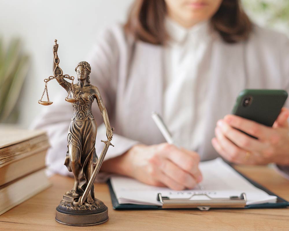 Juriste Veille juridique avec Thémis, statue symbole de la justice, sur son bureau